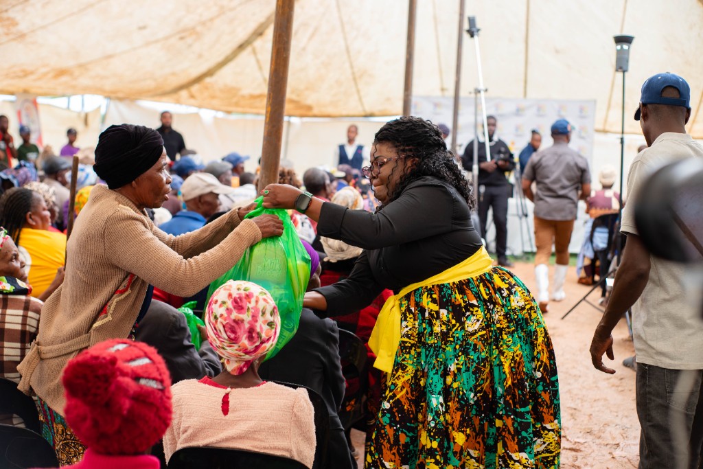 A volunteer handing a Christmas hamper to an elderly resident